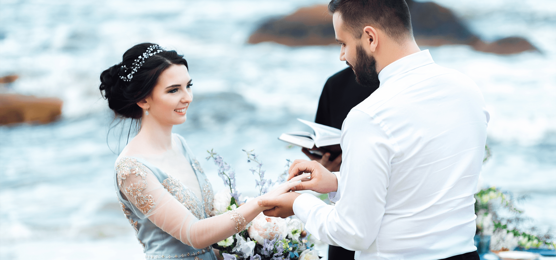 Couple being wed on a rocky shore.